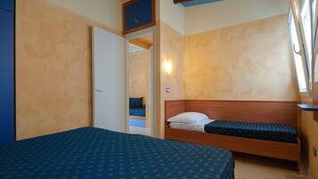 Ein Schlafzimmer mit einem großen Bett, einem kleineren Bett, einem Kleiderschrank und einem Fenster mit Blick.