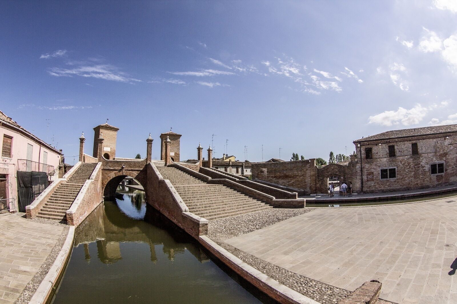 Un pont historique, surmonté d’un canal d’eau, reliant deux bâtiments.