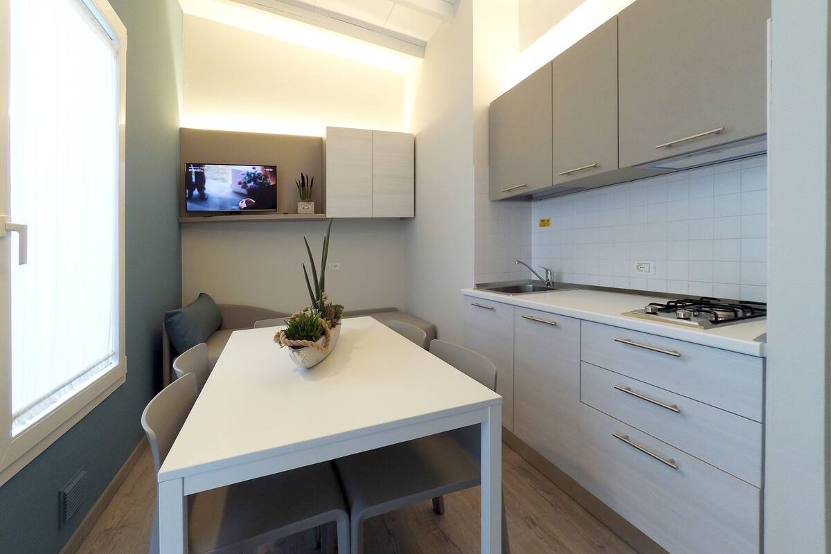 A modern kitchen with white cabinetry, a gas stove, and a dining area with a white table and chairs.