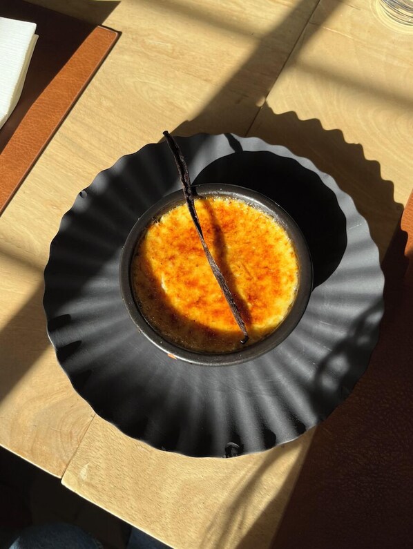 Een dessert in een zwarte kom op een houten tafel.