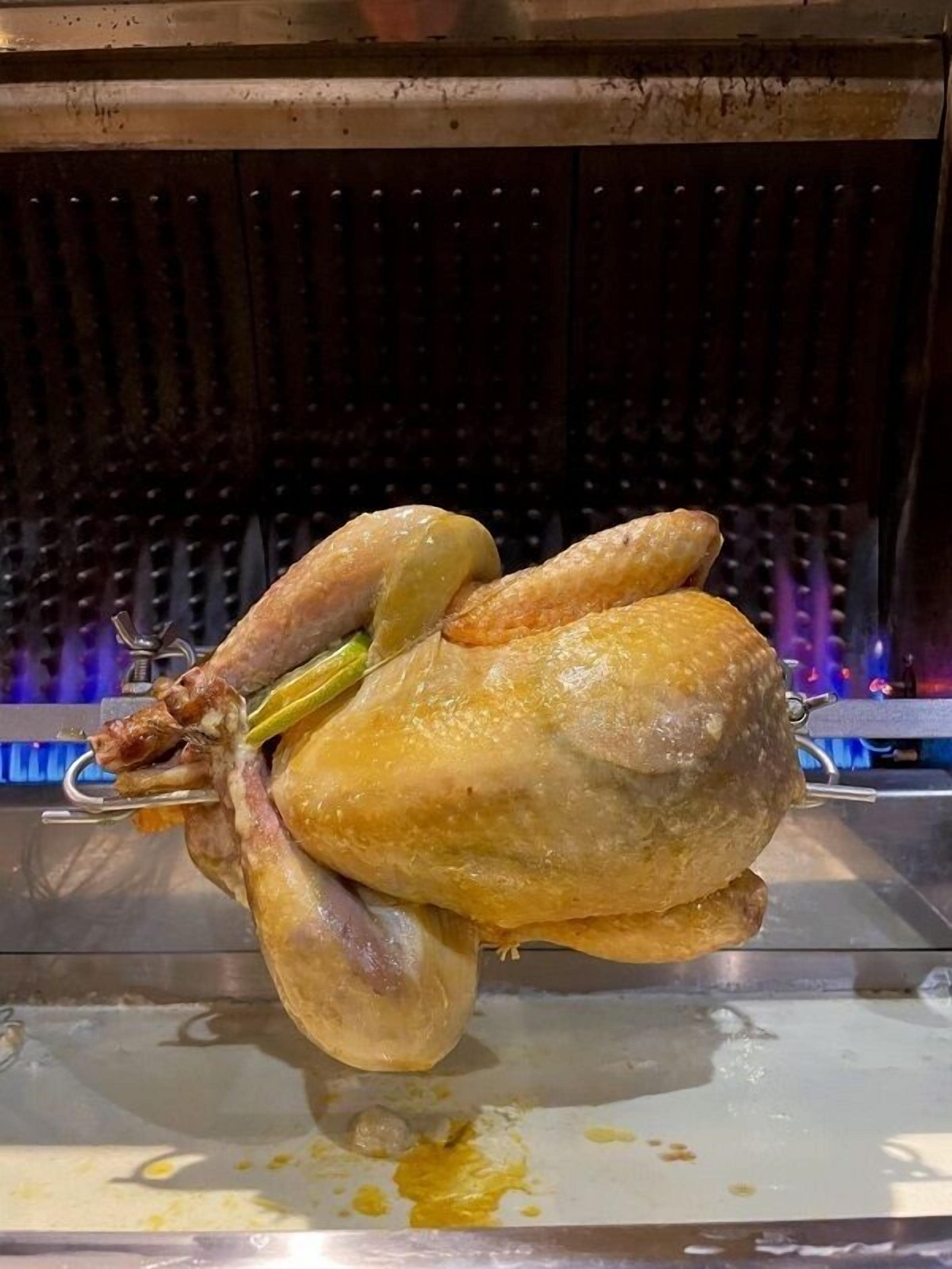 Un pollo entero asado en un asador, en una cocina.