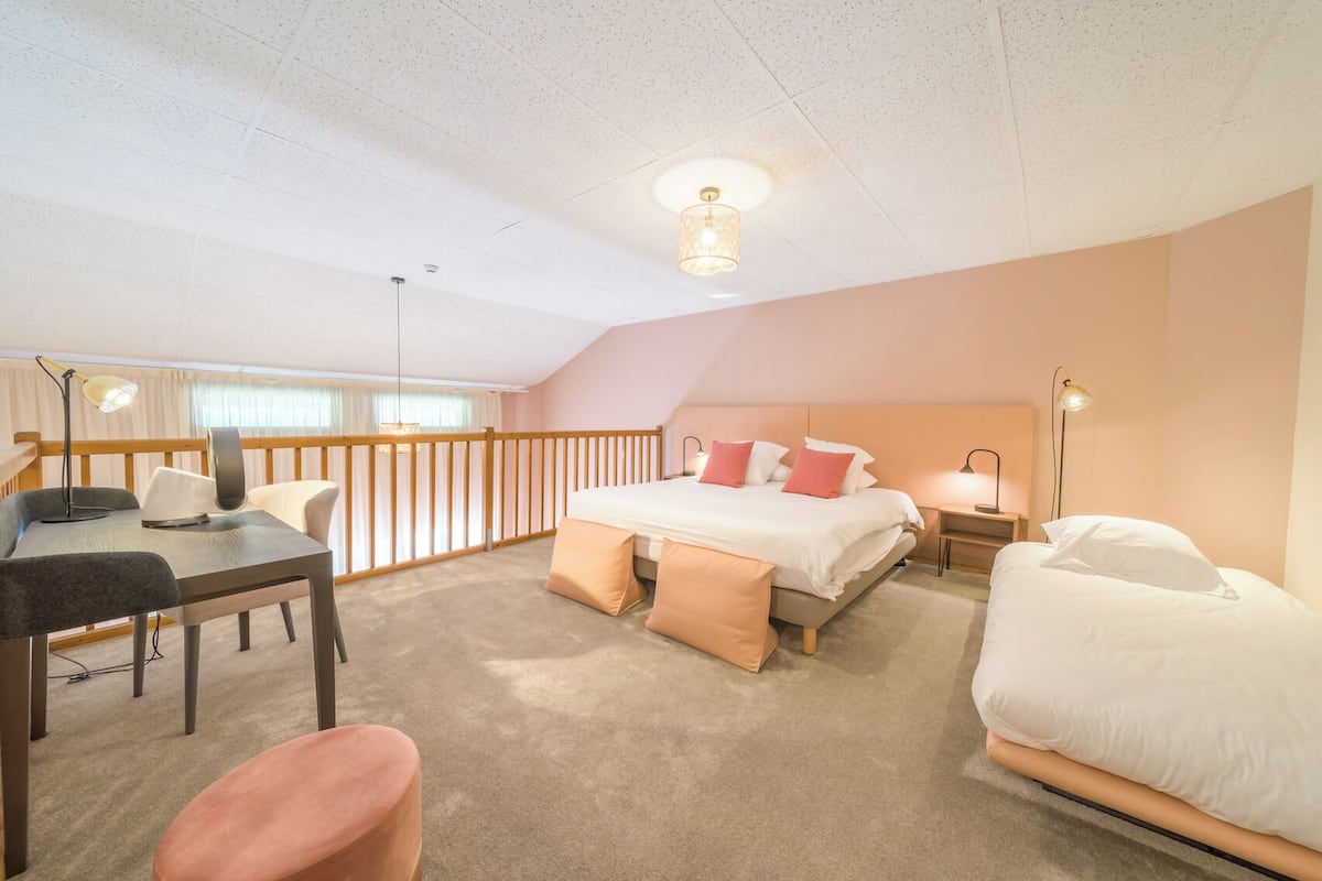 A bedroom with a bed, bedside tables, a desk, and a chair.