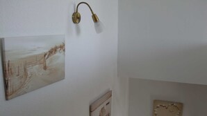 A wall with three framed artworks, a wall-mounted lamp, and a heart-shaped decoration. - 89820 Fw 2 - 89820 Holiday apartment 2 (Malchow)
