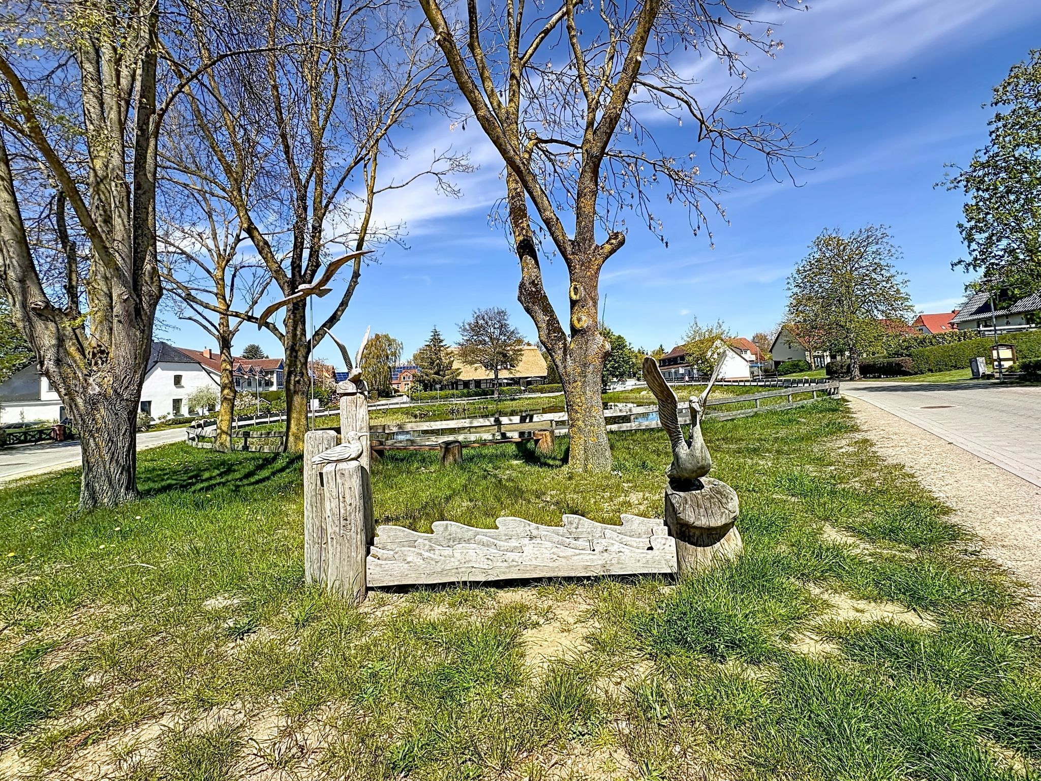 A park with trees, a wooden bench, and a stone sculpture.