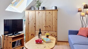 A modern living room with a television, wooden cabinet, table with books and apples, and a sofa. - Gollwitzer Park (Insel Poel) by Interhome (Gollwitz (Insel Poel))