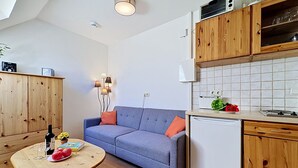 A compact living space with a sofa, wooden cabinets, a small kitchen area, and a dining table. - Gollwitzer Park (Insel Poel) by Interhome (Gollwitz (Insel Poel))