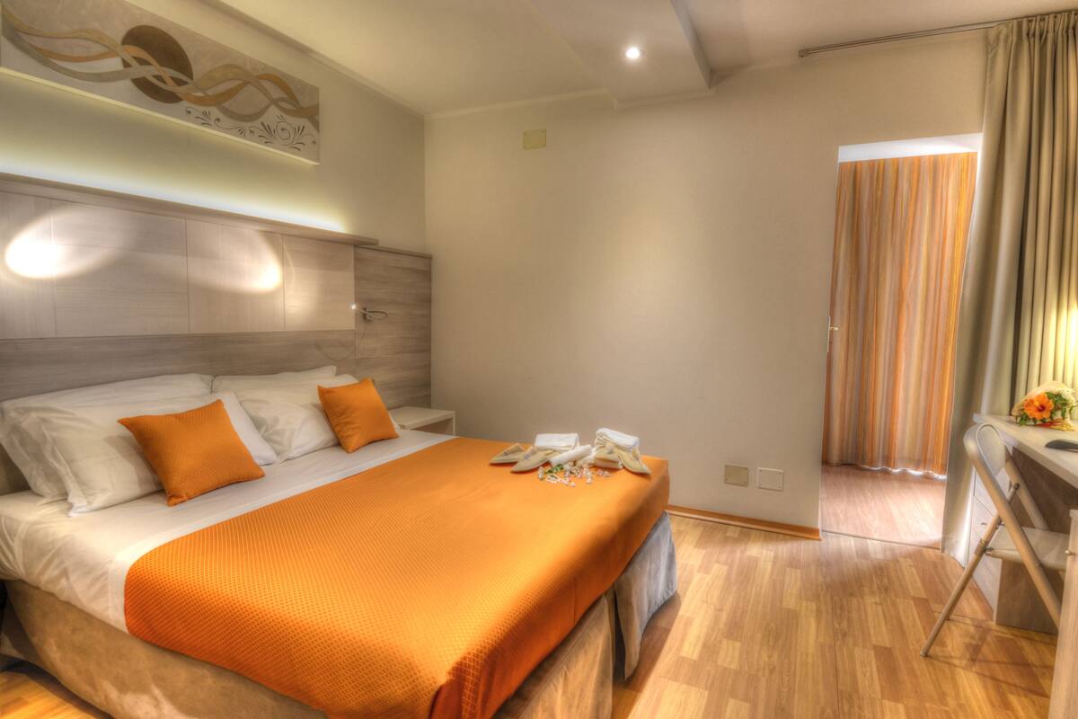 A modern hotel room with a large bed, a desk, and a shower area.