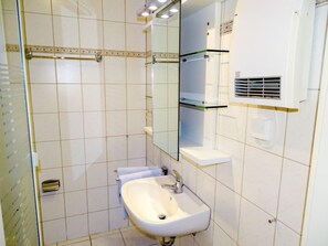 Ein Badezimmer mit weißem Waschbecken, Spiegel und gefliesten Wänden.
