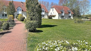 Een rij witte huizen met rode daken, een geplaveid pad en een verzorgd gazon.