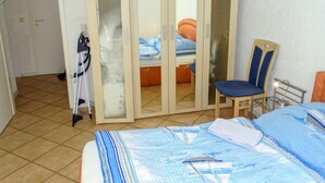 Een slaapkamer met een bed, een stoel, een kledingkast en een deur.