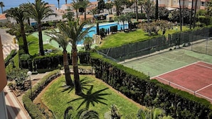 A residential area with a tennis court, pool, and a view of the sea.