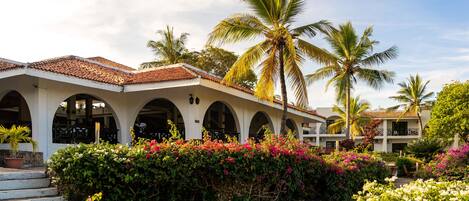 A resort with a white building featuring arched windows and a tiled roof.