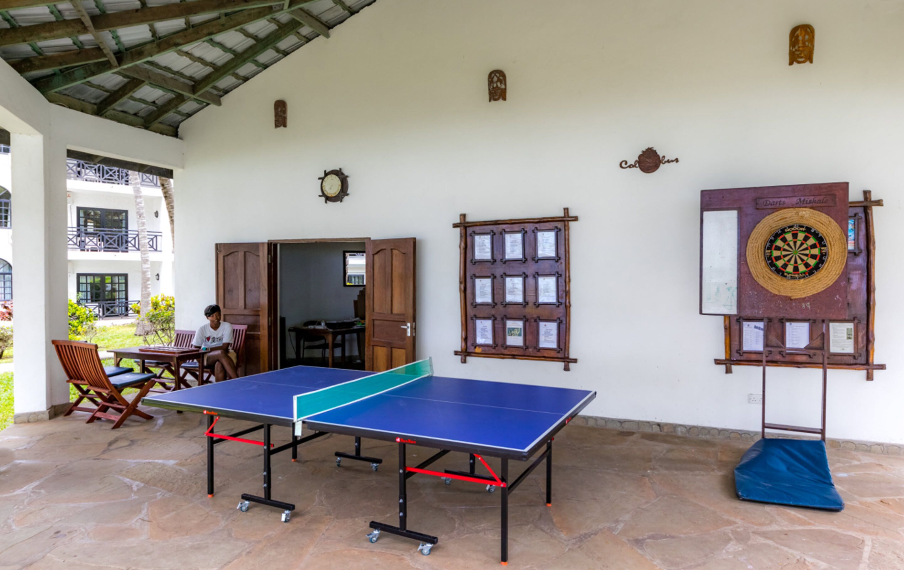 Una habitación con mesa de ping pong, dardo y reloj de pared.