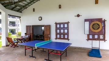 Una habitación con mesa de ping pong, dardo y reloj de pared.