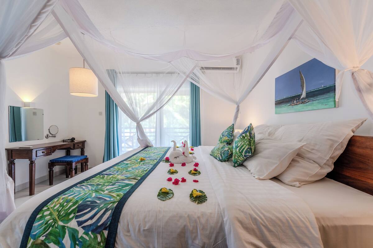 A hotel room with a bed, a desk, and a painting of a sailboat.