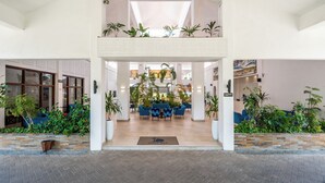 Un'ampia hall con soffitto alto, un'area salotto centrale e diverse piante in vaso.