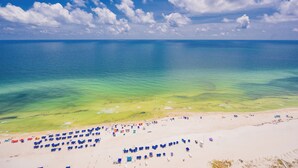 A beach with clear turquoise water, a sandy shore, and numerous umbrellas.