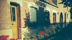 A row of brick buildings with a central entrance and flower beds in front.