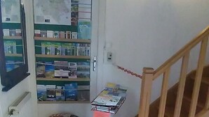 A small room with a wooden staircase, a radiator, a map on the wall, and a small table with magazines.