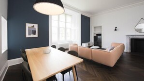 A modern living room with a wooden dining table, a beige sofa, and a black pendant light. - A lews castle that sleeps 4 guests  in 2 bedrooms (Isle of Lewis)