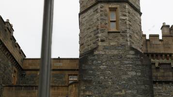 A stone tower with a window, part of a historic building with stone walls and a traditional design.