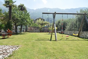 A grassy backyard with a swing set and a small pool.