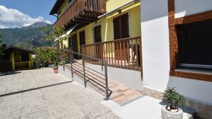 Um edifício com varanda, escadaria e planta em vaso.