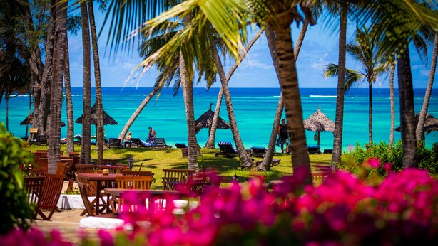A beachside resort with palm trees, lounge chairs, and a view of the ocean. - Diani Sea Lodge (Diani Beach)