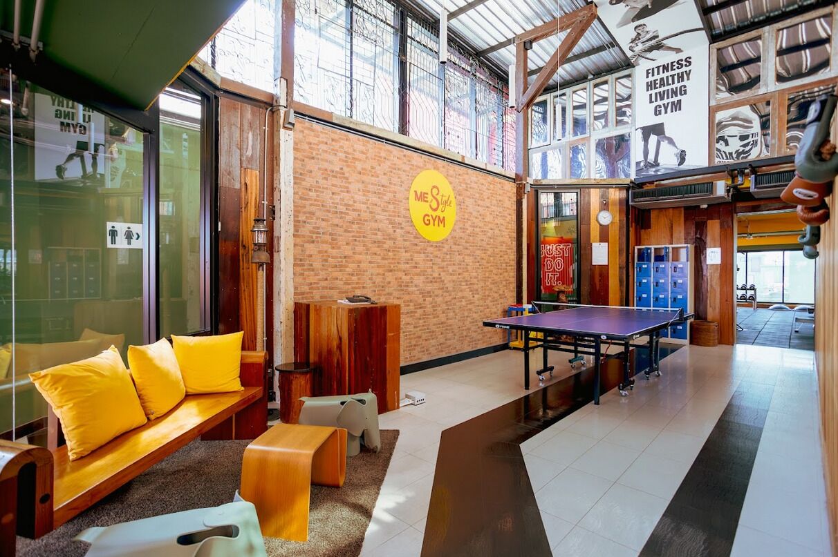 Un gimnasio con mesa de ping pong, bancos de madera y taquillas.
