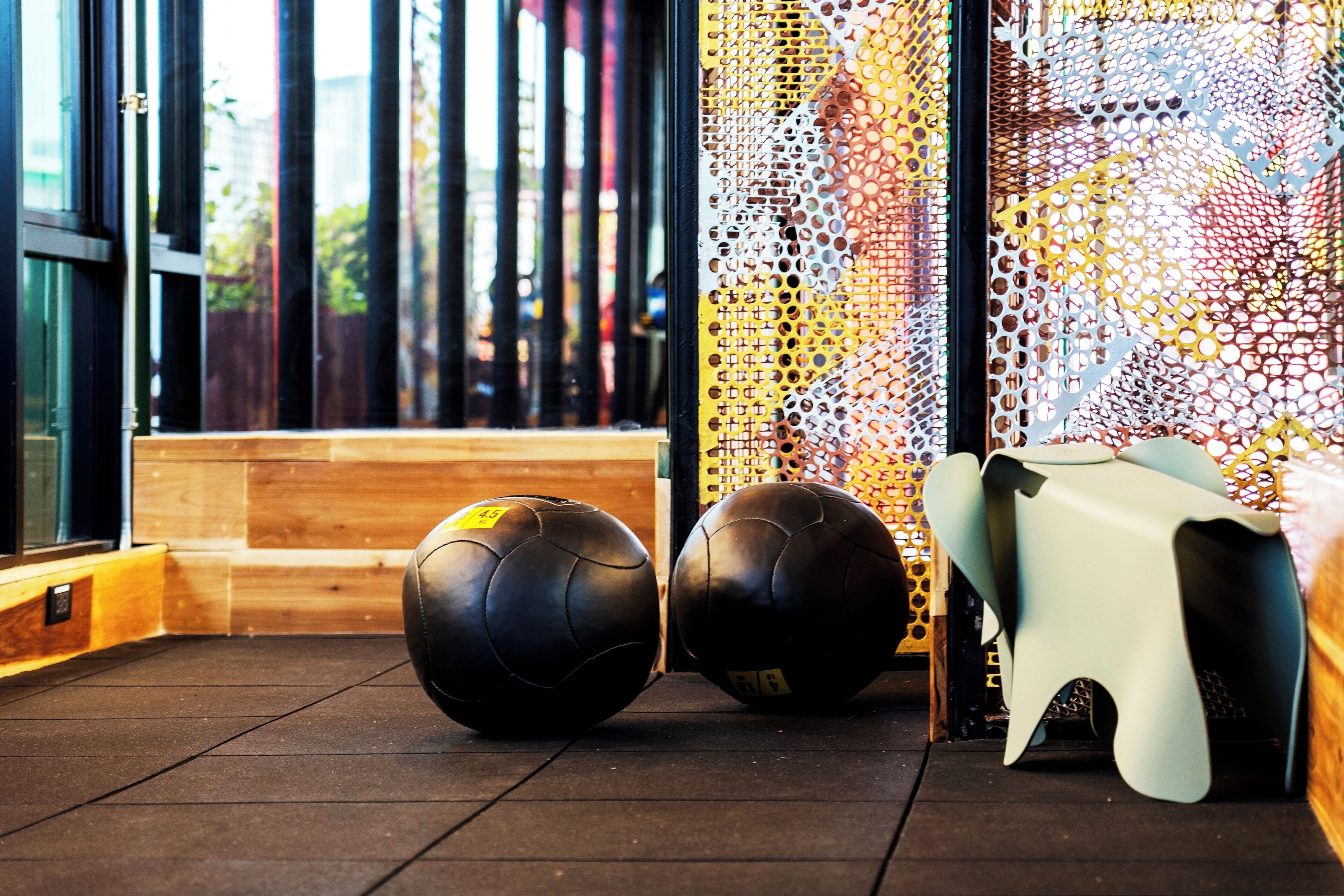 Une salle de sport équipée de matériel d’exercice, d’un banc en bois et d’un mur orné d’un motif géométrique.