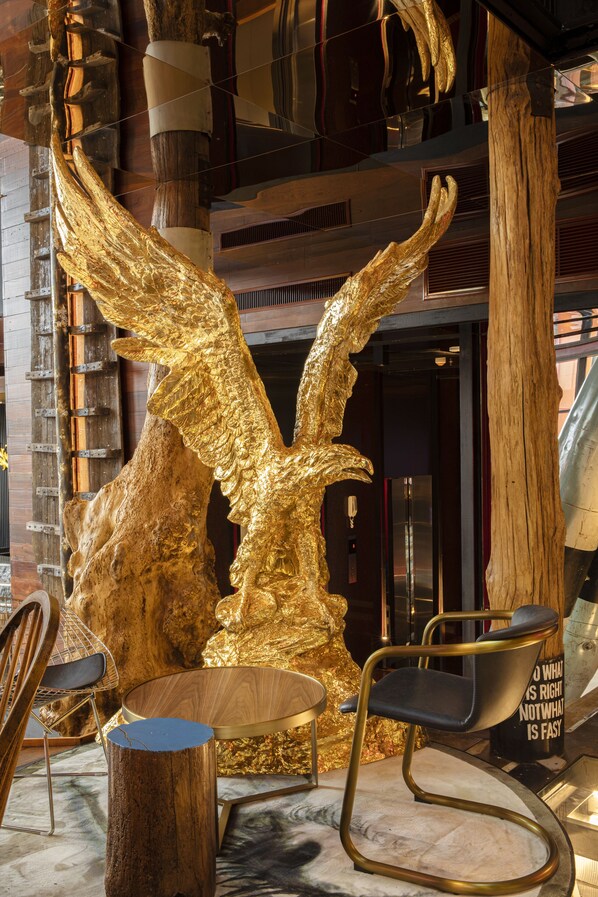 A modern interior with a large golden sculpture, a wooden chair, and a unique black chair with a message on the backrest. - MeStyle Museum Hotel (Bangkok)