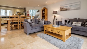 Ein modernes Wohnzimmer mit grauem Sofa, Couchtisch aus Holz und einem Gemälde an der Wand.
