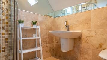 Une salle de bain avec une douche à parois de verre, un lavabo sur colonne blanc et un mur miroir.
