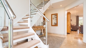 Eine moderne Treppe mit Glastrennwand und beigefarbenen Teppichstufen.