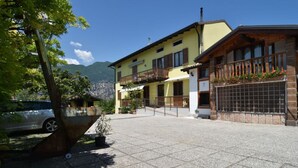 Un hôtel avec une cour dallée, une voiture garée à proximité et une montagne en arrière-plan.