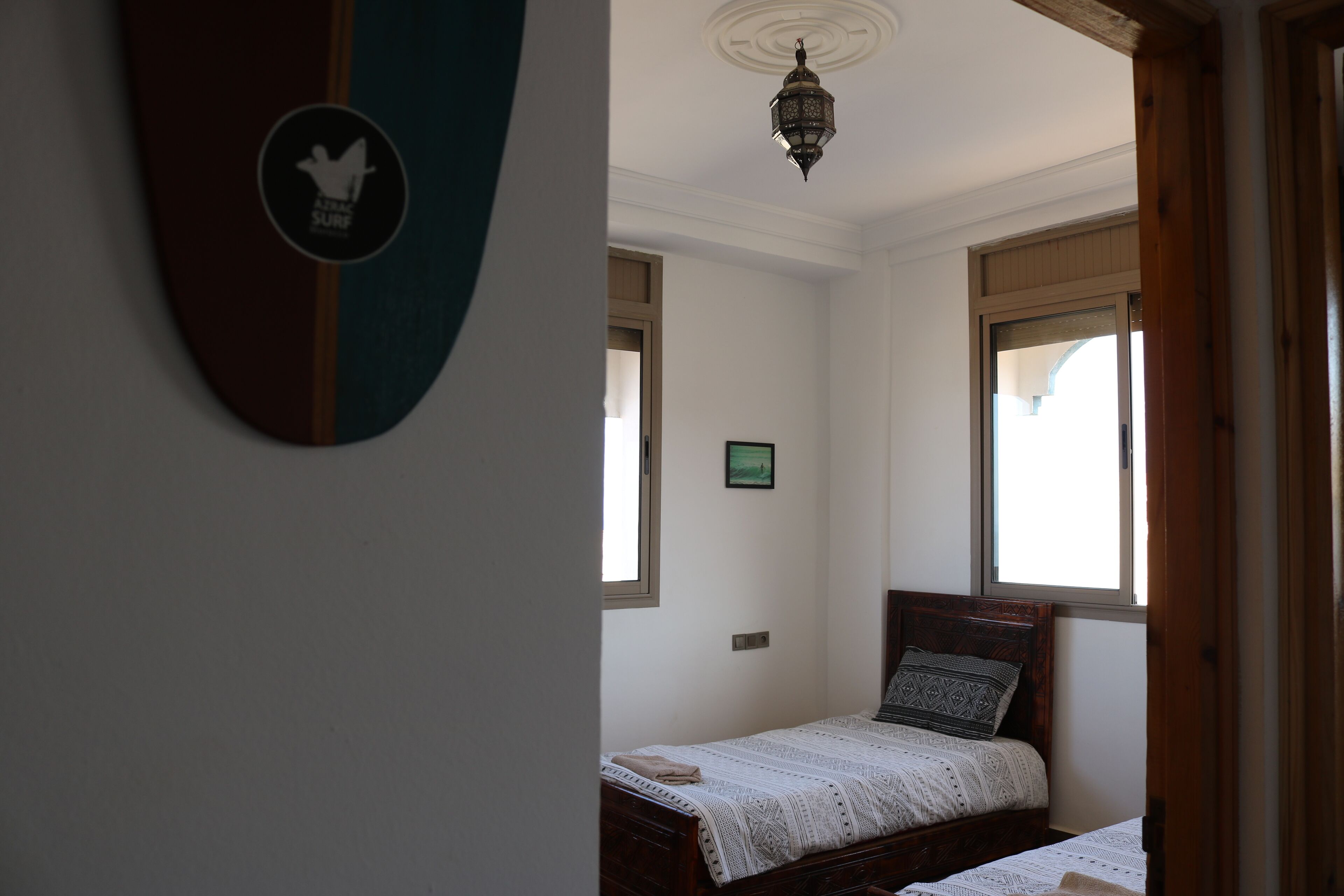 Un dormitorio con una cama, una lámpara en la pared y una ventana.