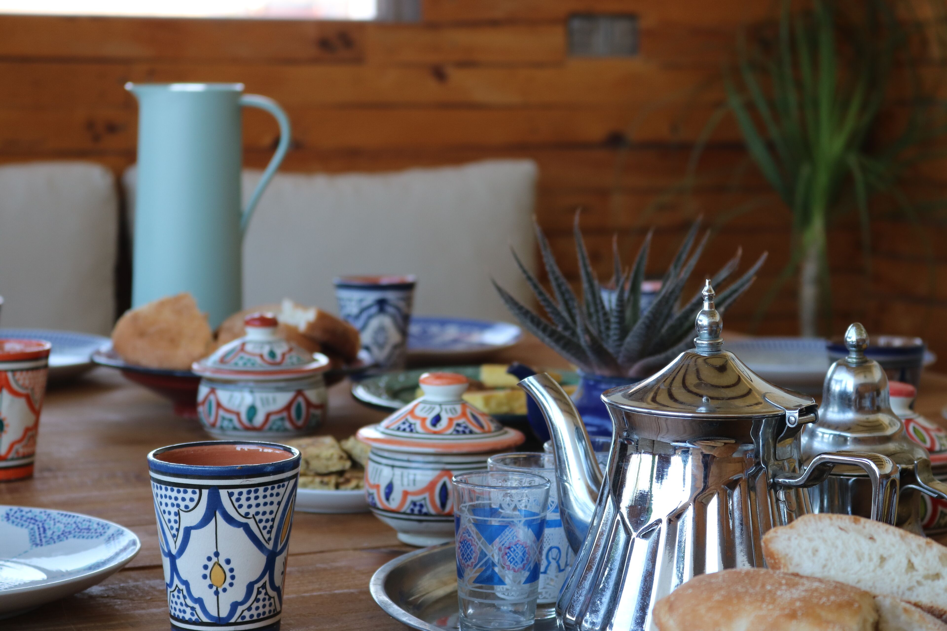 A dining table with Moroccan-style tableware, including a teapot, cups, and plates, suggesting a cultural dining experience.
