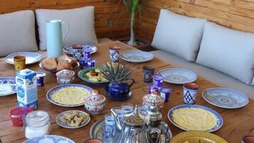 A dining table set with various plates, cups, and a pitcher, surrounded by wooden benches and cushions.