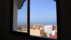 A window with a view of a coastal town and the sea. - Azrac Surf Morocco (Aourir)