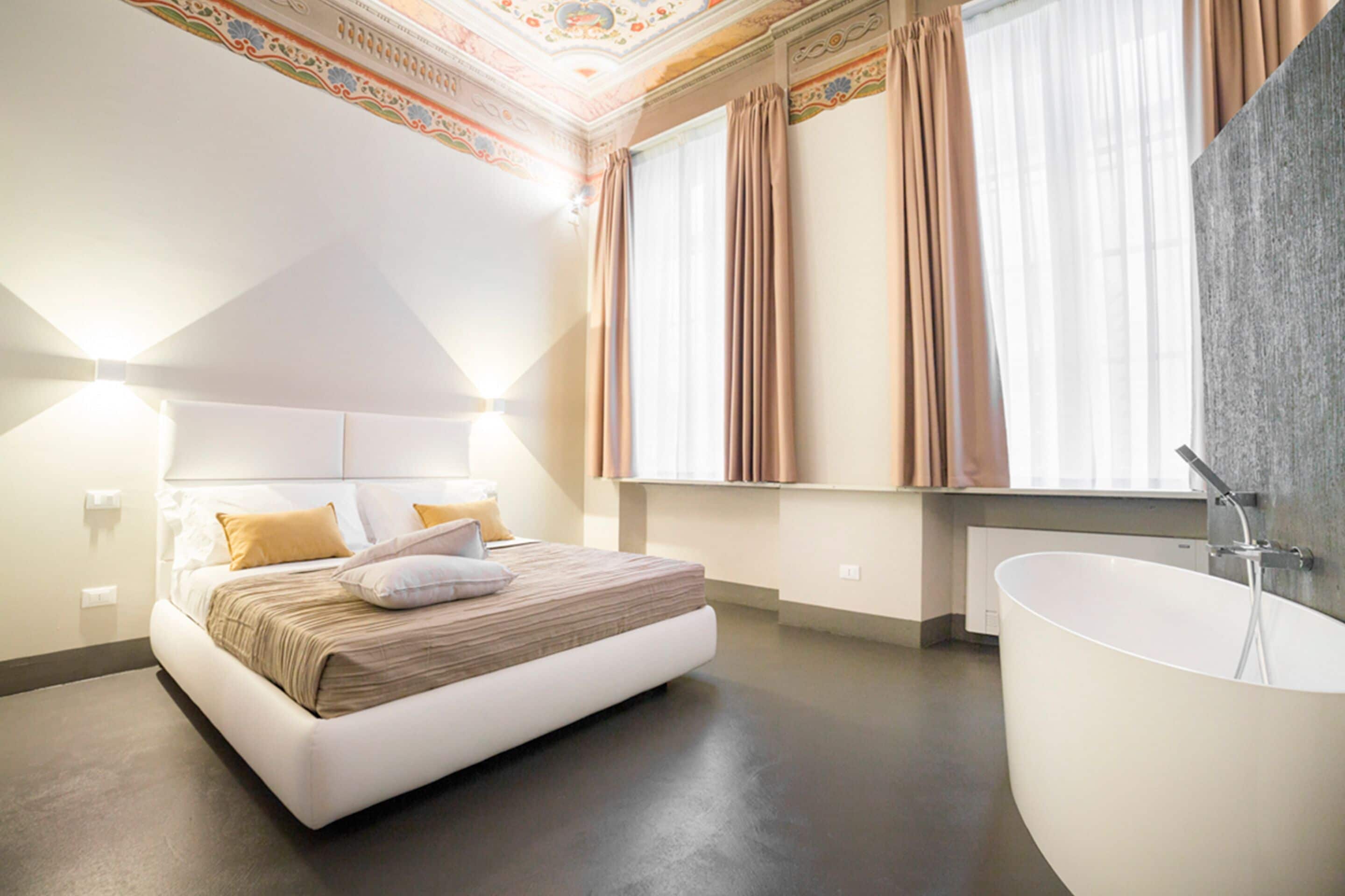 Un dormitorio moderno con una cama grande, una bañera integrada y un techo decorativo.