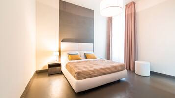 A modern hotel room with a large bed, a bedside table, a lamp, and a large window with curtains.