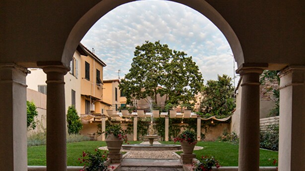 An arched corridor with stone flooring, columns, and potted plants. - LUCUS Exclusive B&B (Lucca)