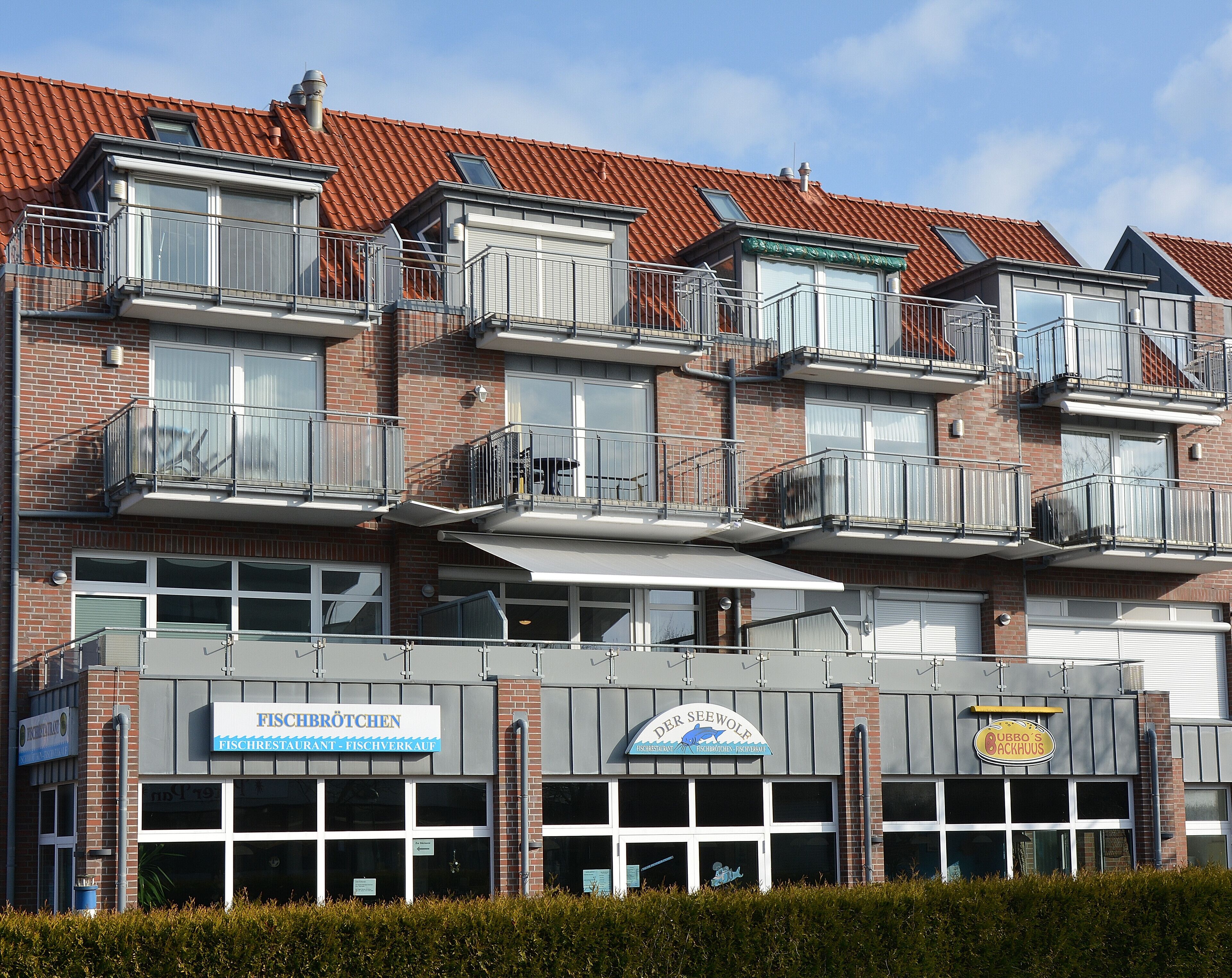 Un immeuble à plusieurs étages doté de balcons, un restaurant de poissons et une boutique de produits de la mer.