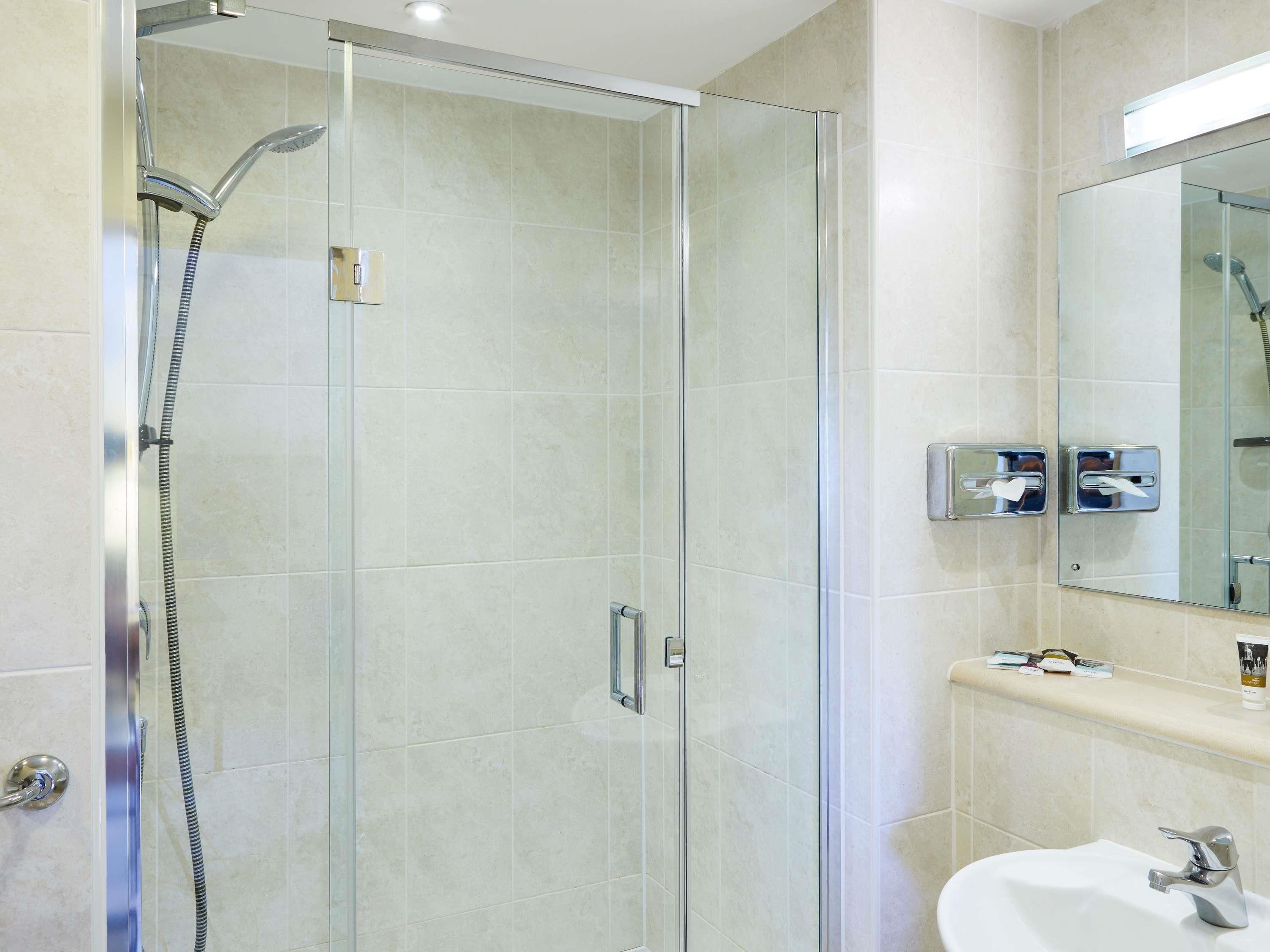 A modern bathroom with a glass-enclosed shower, a white sink, and a mirror above the sink.