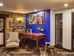 A room with a stone wall, a blue accent wall, a wooden table, a chair, and a small stool. - Mercure Barnsley Tankersley (Barnsley)