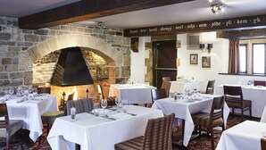 Um restaurante com paredes de pedra, vigas de madeira e mesas preparadas para refeições.