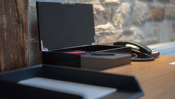 A desk with a closed black box, a telephone, and a wooden surface.