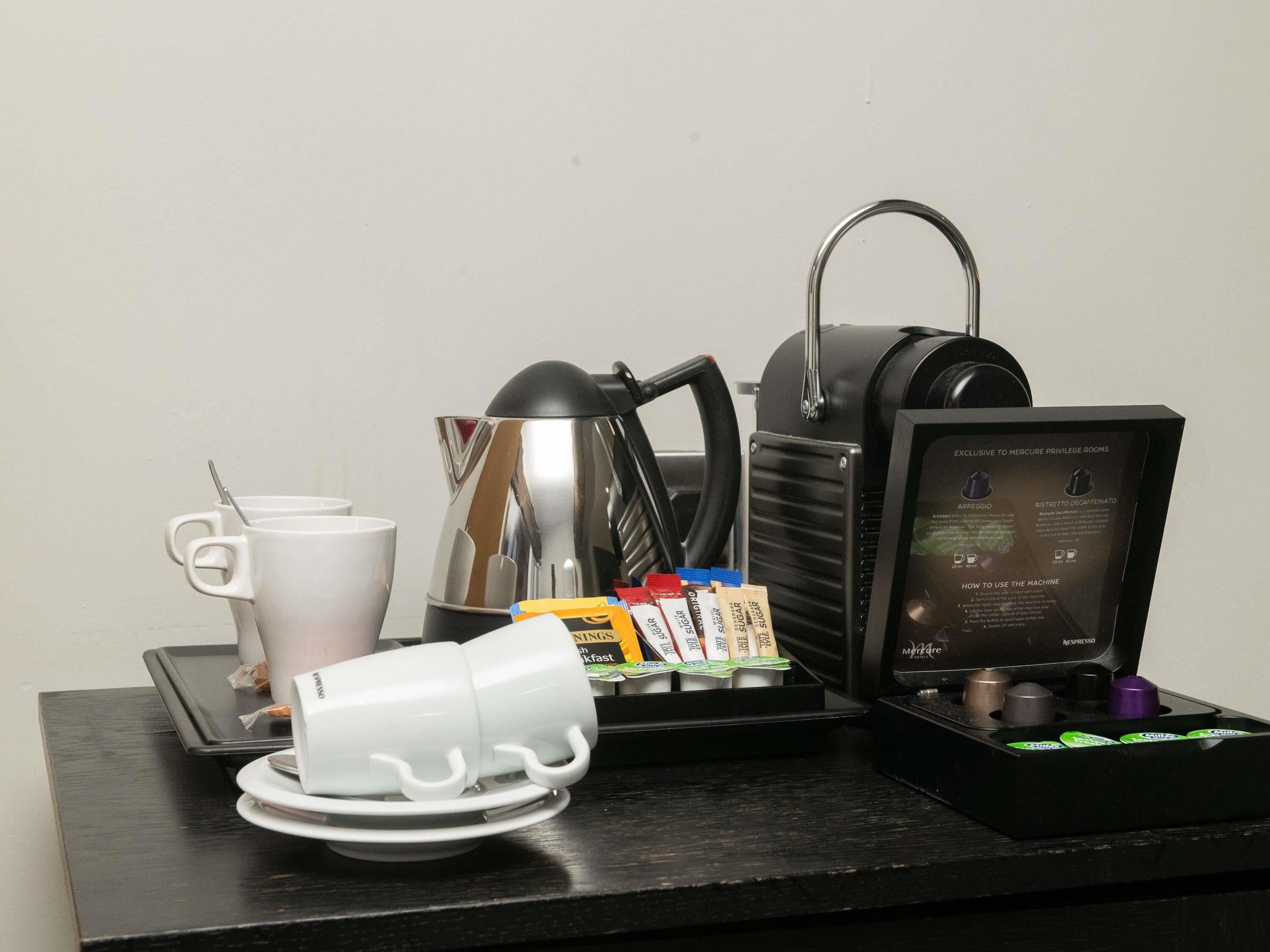 Una máquina de café, tazas de café y cápsulas de café sobre una mesa.