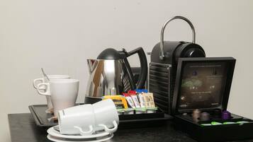 Una máquina de café, tazas de café y cápsulas de café sobre una mesa.