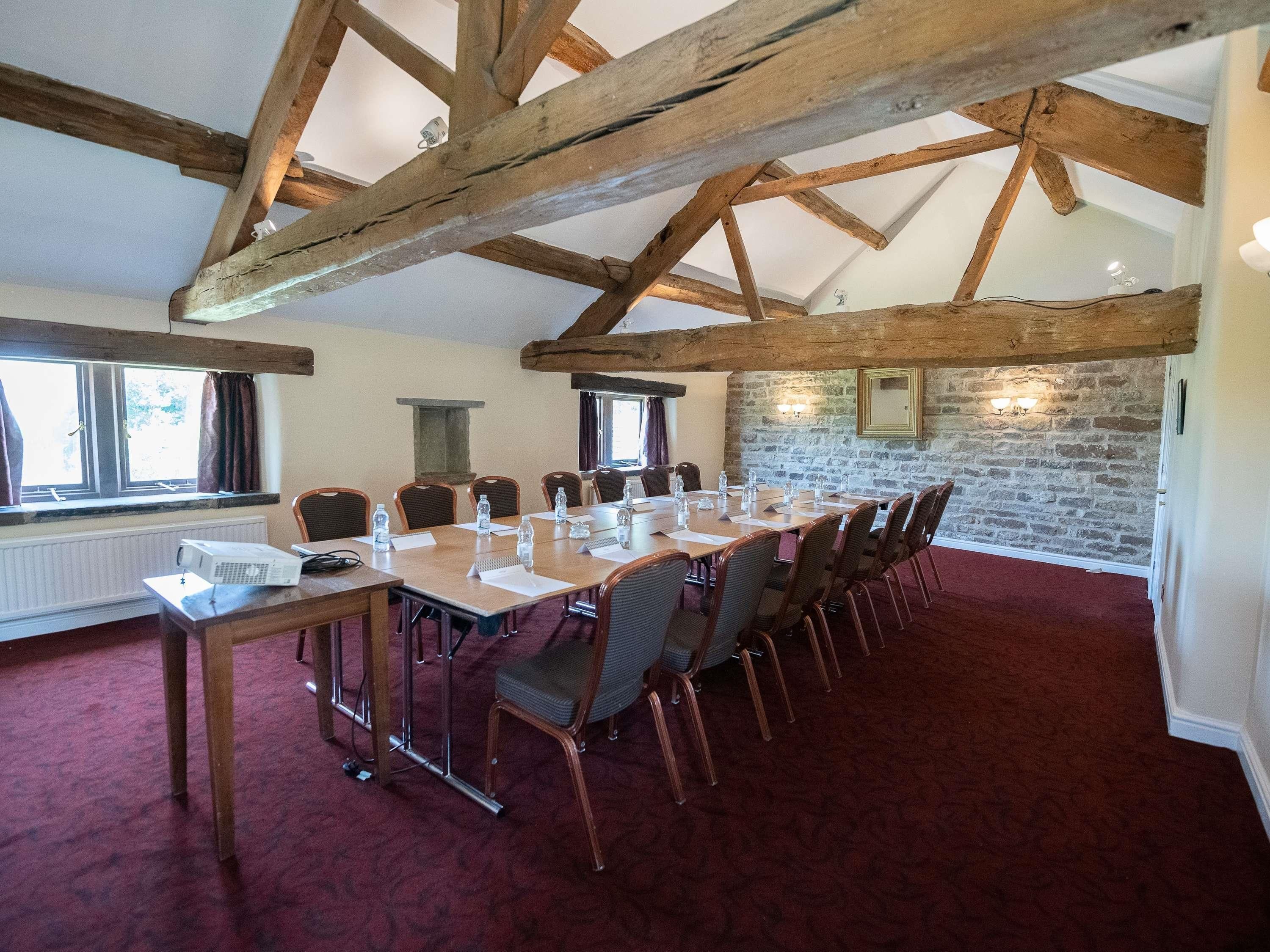 A conference room with a long table, chairs, a projector, and a stone wall.